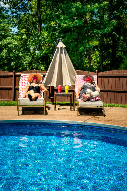 Two women wearing face masks are social distancing at the swimming pool on a hot summer day, Indiana, USA