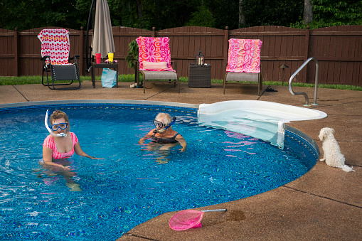 Two females  wearing snorkel face masks cool off in a swimming pool during Covid-19, Indiana, USA