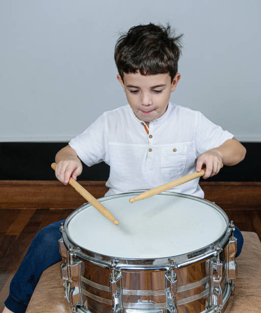 istock 7 year old child concentrated and playing drums. 1263738440