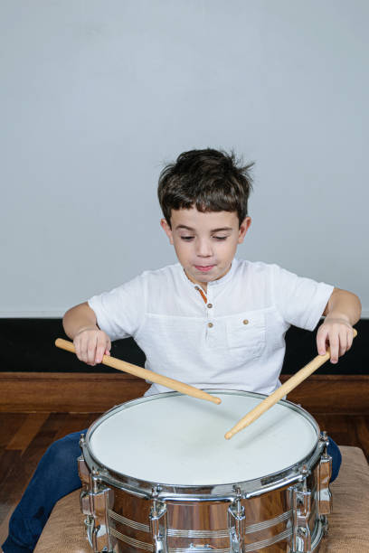 istock 7 year old kid playing the drums and making a funny face. 1263738546