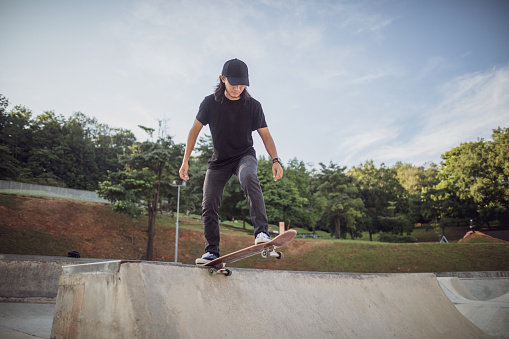 Asian man playing skateboard at skatepark