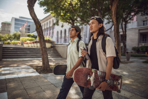 Asian man playing skateboard at town