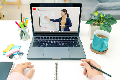 Point of view of young asian girl sit on desk and learn at home living room in concept of romote learning, virtual online, self isolated quarantine lifestyle in asia. Teaching video call on computer.