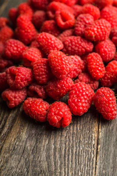 istock Freshly harvested raspberry on the rustic wooden background 1263758897
