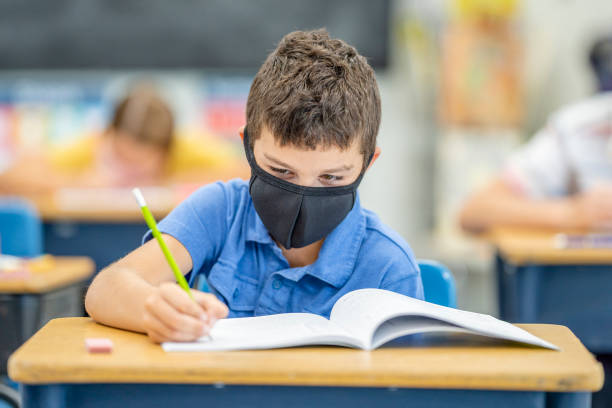 istock Young student wearing a protective face mask in the classroom 1263760318