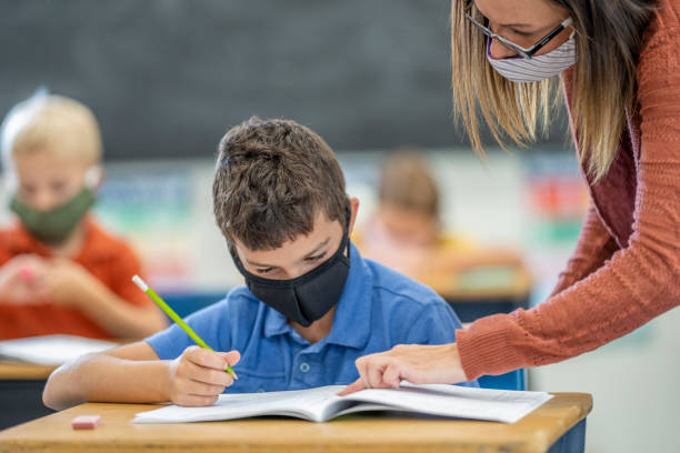 istock Elementary school student and teacher wearing masks in the classroom 1263760327