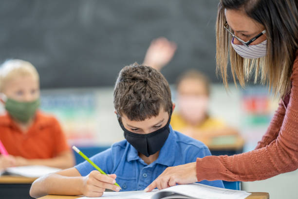 istock Elementary school student and teacher wearing masks in the classroom 1263760332
