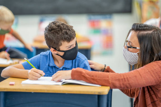 istock Elementary school student and teacher wearing masks in the classroom 1263760333