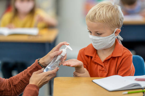 istock Teacher supplying students with hand sanitizer 1263760359