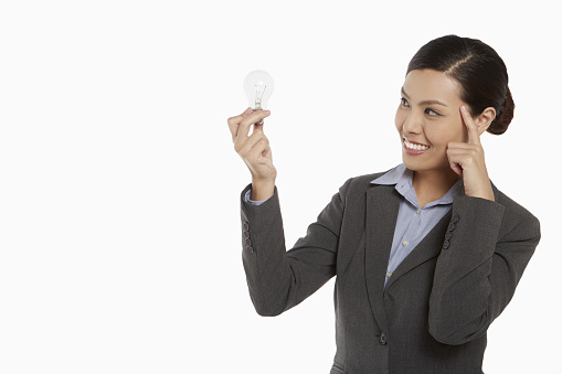 Businesswoman smiling and holding up a light bulb