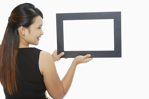 Woman holding up a black picture frame