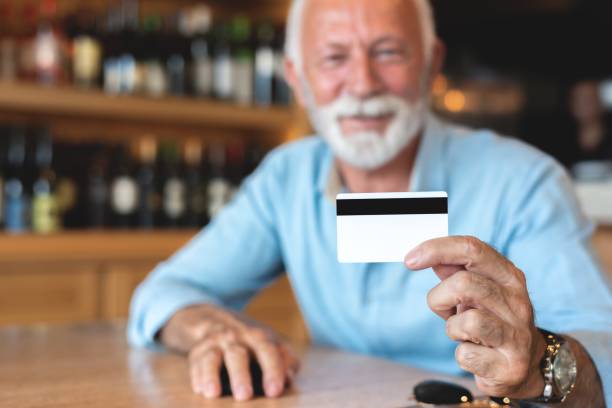 istock Senior man showing credit card at restaurant 1263770575