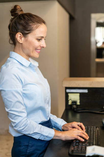 istock Young female receptionist at hotel front desk 1263773377