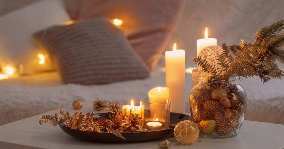 Decoración navideña con velas encendidas sobre mesa blanca sobre el fondo de sofá con a cuadros y almohadas. Acogedor concepto de casa y vacaciones photo