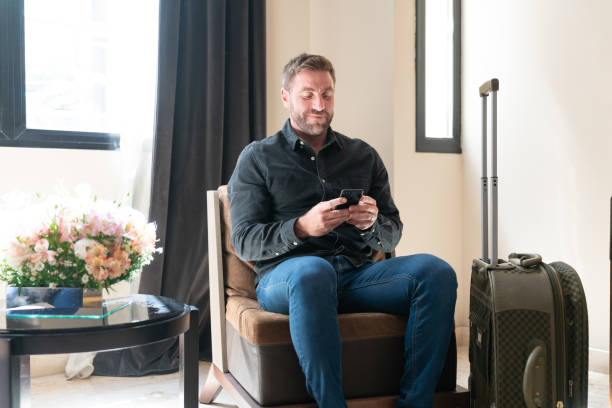 istock Middle aged guest using smartphone at hotel lobby 1263776030
