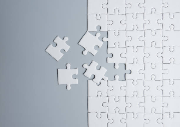 istock Unfinished white jigsaw puzzle pieces on gray background 1263778944