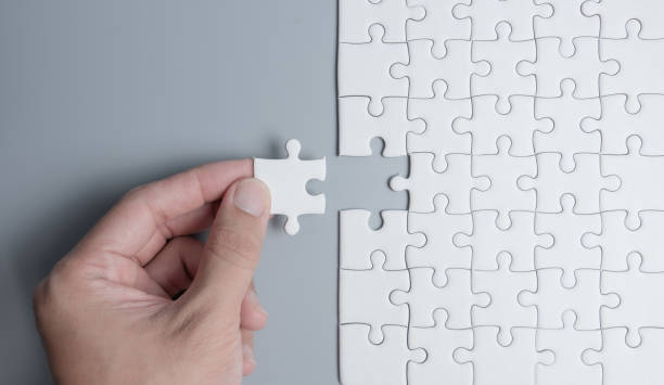 istock Hand putting the last piece in the puzzle on grey background 1263778953