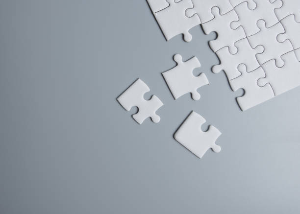 istock Unfinished white jigsaw puzzle pieces on gray background 1263778958