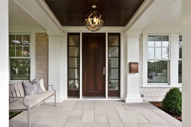 Stone front porch and wood door with vertical windows on each side of the door