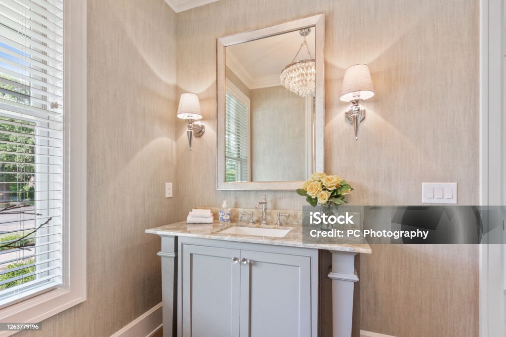Decorative vanity sink and mirror Wall sconce on each side of mirror in lovely powder room Bathroom Stock Photo