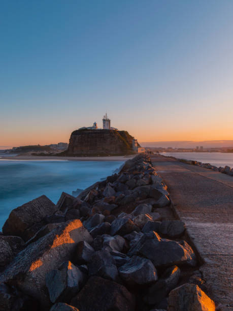 Sunset at Nobbys lighthouse Sunset view of Nobbys lighthouse from the breakwall. newcastle australia stock pictures, royalty-free photos & images