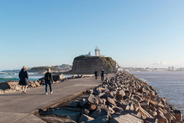 Newcastle, Australia - July 29, 2020: People walking along Newcastle breakwall on a sunny afternoon.