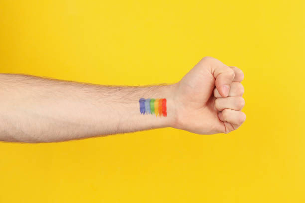 istock Male hand with LGBT rainbow on yellow background, space for text 1263785253