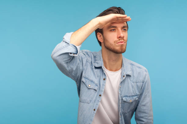 muito futuro. retrato de homem bonito em camisa de jeans trabalhador olhando para a distância, segurando a mão sobre os olhos - hands covering eyes - fotografias e filmes do acervo