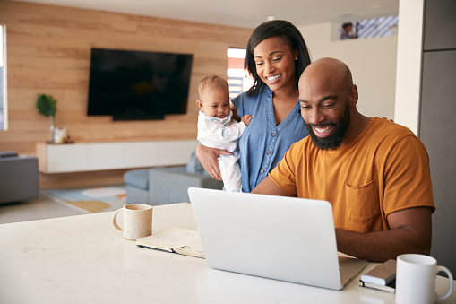 Afroamericana Familia con hija bebé usando portátil para comprobar las finanzas en casa photo