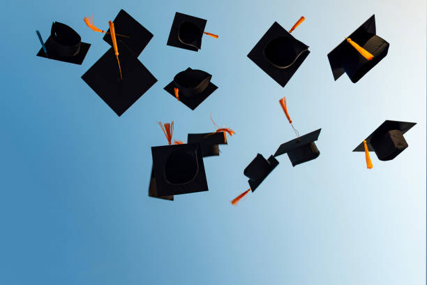 istock Graduates throw black hats in the sky. 1263791150