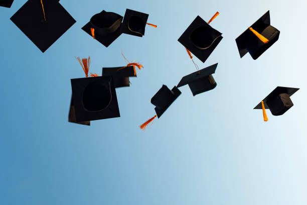 istock Graduates throw black hats in the sky. 1263791152