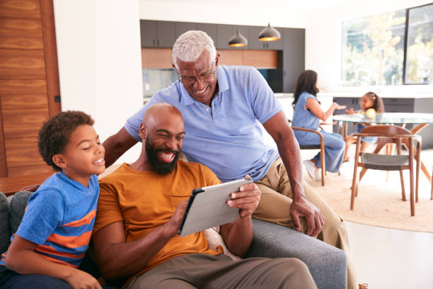istock Multi-Generation Male African American Family Sitting On Sofa At Home Using Digital Tablet 1263793569