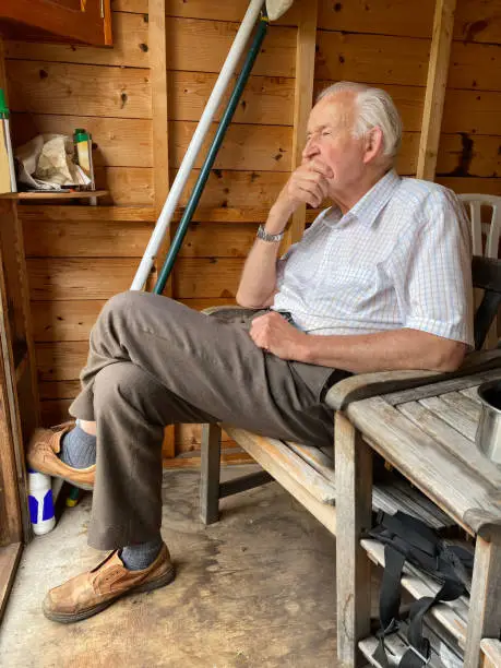 Senior man in garden shed relaxing in retirement uk