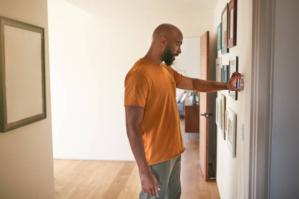 hombre ajustando termostato de calefacción central digital en casa - termostato fotografías e imágenes de stock