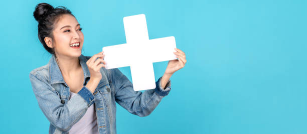 banner de la mujer asiática feliz sonriendo y sosteniendo más o añadir signo en copiar el espacio de fondo azul. chica asia linda sonriendo usando camisa de jeans casual y mostrando signo de unión para increse y más concepto - booked fotografías e imágenes de stock