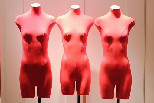 Red figures of a mannequin. Shop window with stripped mannequins. Sale color red. Soft light.