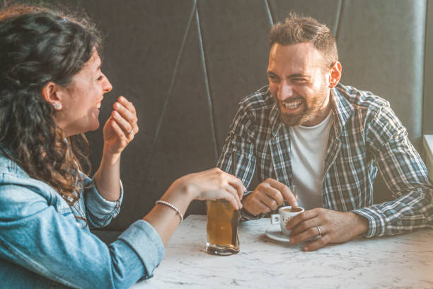 verlobtes paar lacht und scherzt in einer bar - freunde haben spaß beim trinken in einer kaffeebar - warmer filterkontrast - coffee couple italy drinking stock-fotos und bilder