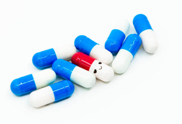 smile faccia capsula rossa con capsule blu su sfondo bianco - anticancer foto e immagini stock
