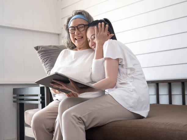 anziana donna asiatica si diverte a leggere con sua nipote. - grandparent senior adult child reading foto e immagini stock