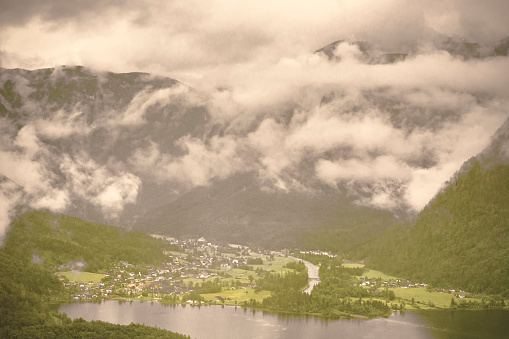 Rain and clouds on the Obertraun in Austria. Morning mist over the Austrian landscape with lake Hallstattersee, forests, fields, pastures and meadows. Retro style