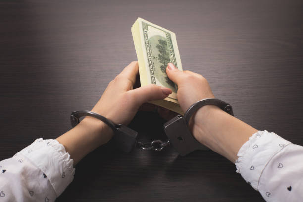 istock hands in handcuffs holding paper money 1263820153