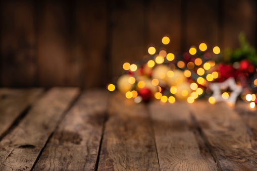 Christmas backgrounds: empty rustic wooden table with defocused Christmas lights at background. Ideal for product display. Predominant colors are brown and yellow. High resolution 42Mp studio digital capture taken with Sony A7rII and Sony FE 90mm f2.8 macro G OSS lens