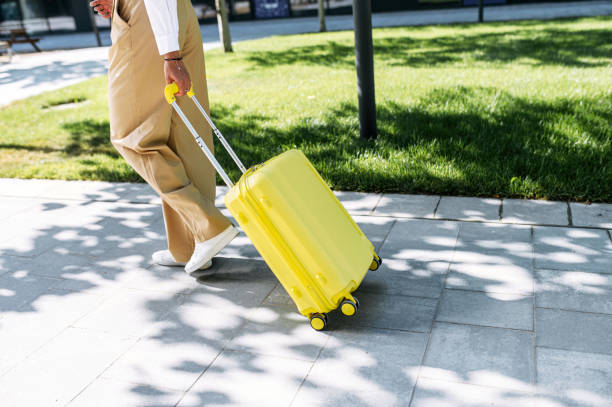 istock Female hands pull a yellow trolley bag outdoors 1263825749