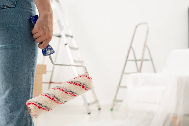 Holding paint roll Close-up of unrecognizable woman in jeans holding paint roll in room with stepladders house painter ladder paint men stock pictures, royalty-free photos & images