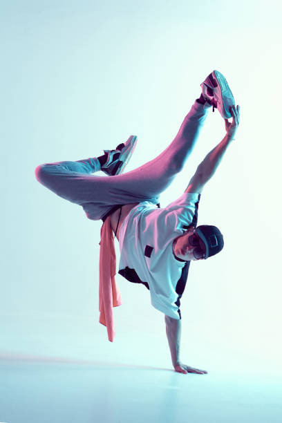 Young breakdancer guy stands on one hand dancing hip-hop in neon light. Dance school poster