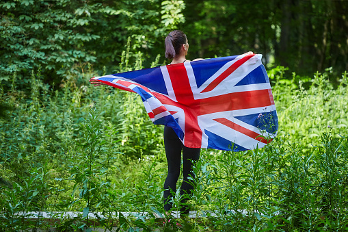 attractive girl posing with the flag of Great Britain in a forest park