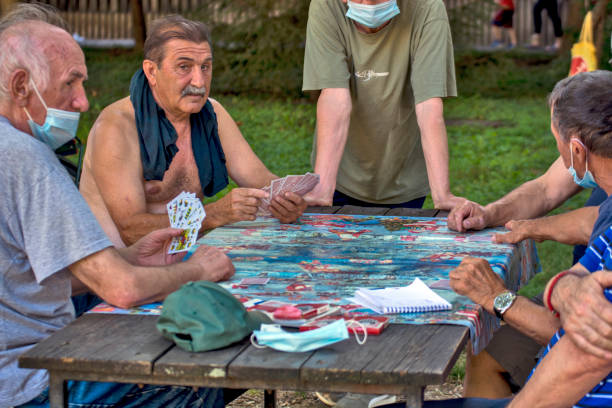 Zrenjanin, Serbia, July 29, 2020. Older gentlemen and pensioners play cards every day in the shade of a large tree. There are always curious observers.