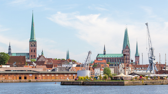 Travemünde, Schleswig-Holstein / Germany - June 24, 2020: Cityscape of Lübeck with church steeples. Incl. St. Jakobi (left), Marienkirche (right) and St. Petri (just next to the crane on the right).