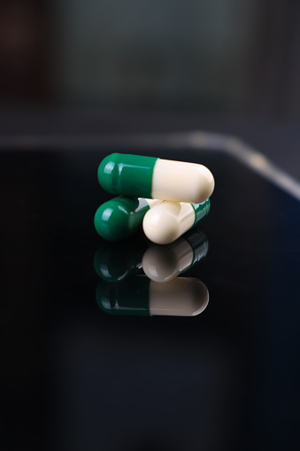Green and white capsules in a dark background