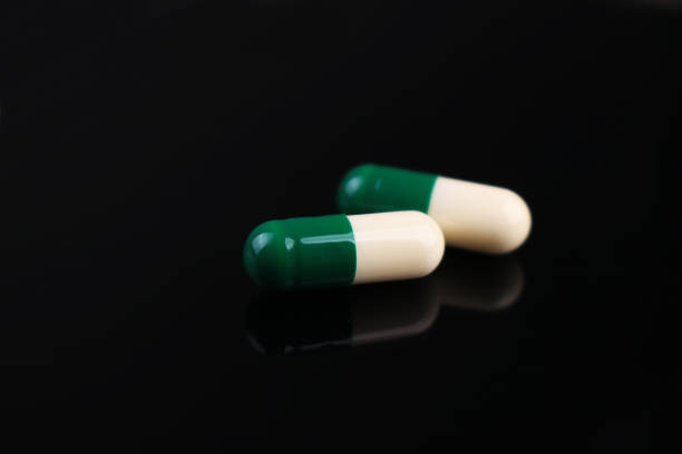 istock Green and white capsules in a dark background 1263842798